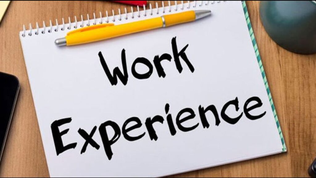 A notebook with the words 'Work Experience' written on it, accompanied by a yellow pen, representing the concept of professional experience and career development.